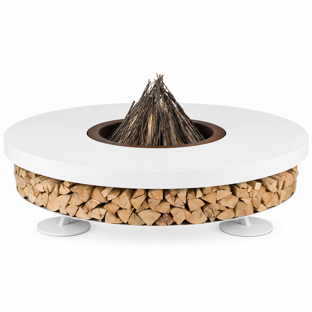 A round outdoor fire pit table with a white top, a wood-burning insert with a pile of branches, a base filled with stacked firewood, and small white pedestal legs, shown on a plain white background.